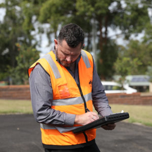 Adam Pinkerton with clipboard assessing an asphalt project