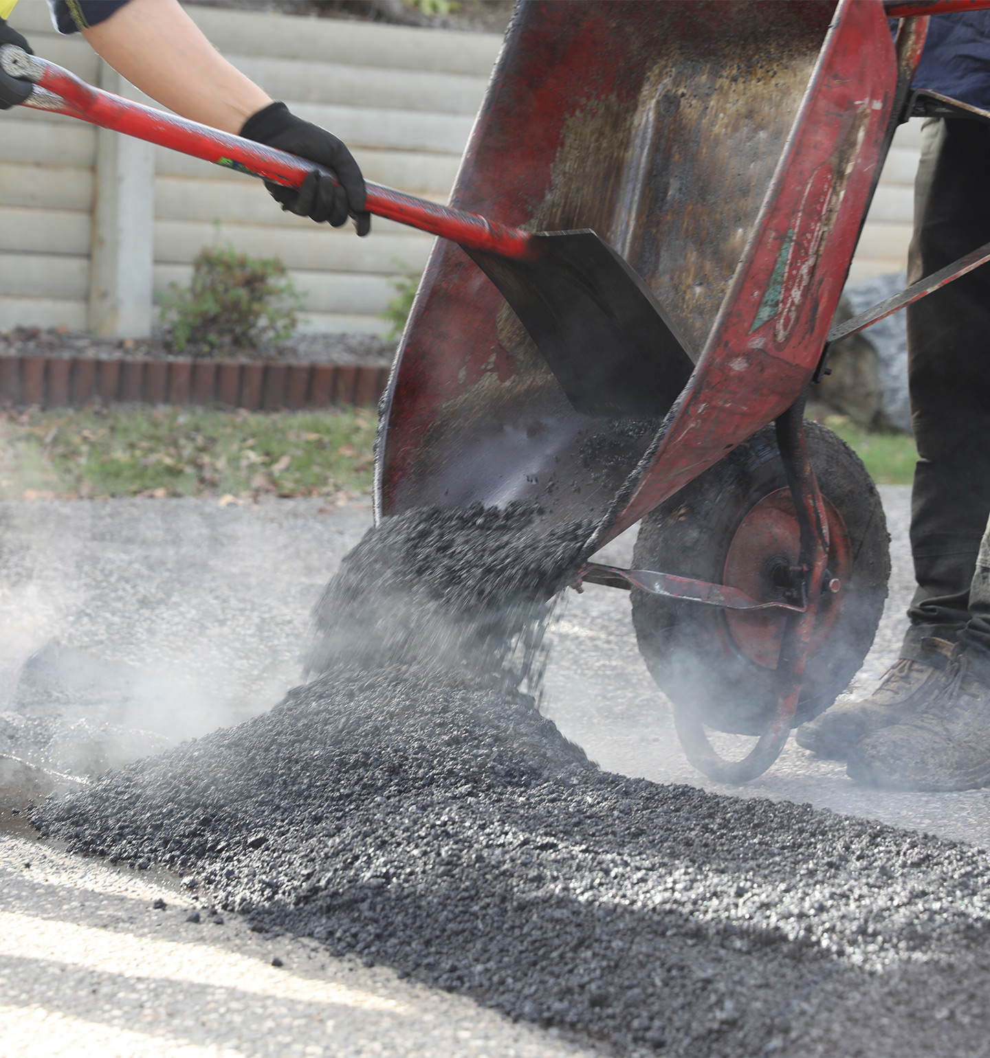 Tipping asphalt from wheelbarrow using spade