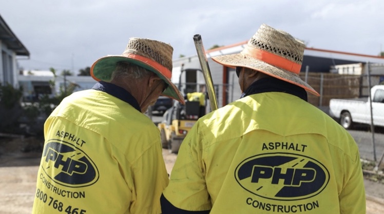 Back of 2 Pothole People Qld staff members with company high visibility tops on.